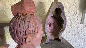 Self-portrait head sculpture next to a sarcophagus